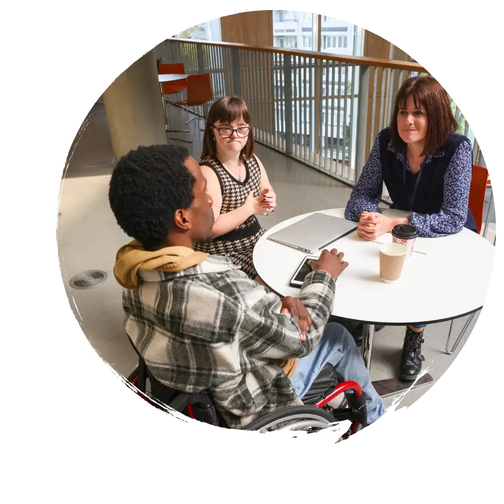 Disabled man in wheelchair and woman with down syndrome talking with support worker